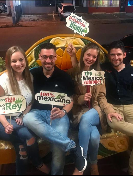 Clients having celebrating at the restaurant holding mexican signs.