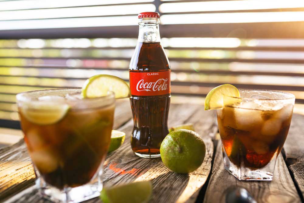 Coca-cola bottle with two glasses with lemon